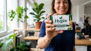 Main tenant une boîte Hygée, sourire confiant, bureau moderne, plantes vertes.