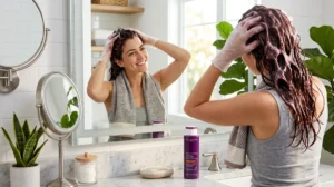 Femme souriante appliquant le shampoing colorant Novara dans une salle de bain moderne et lumineuse.